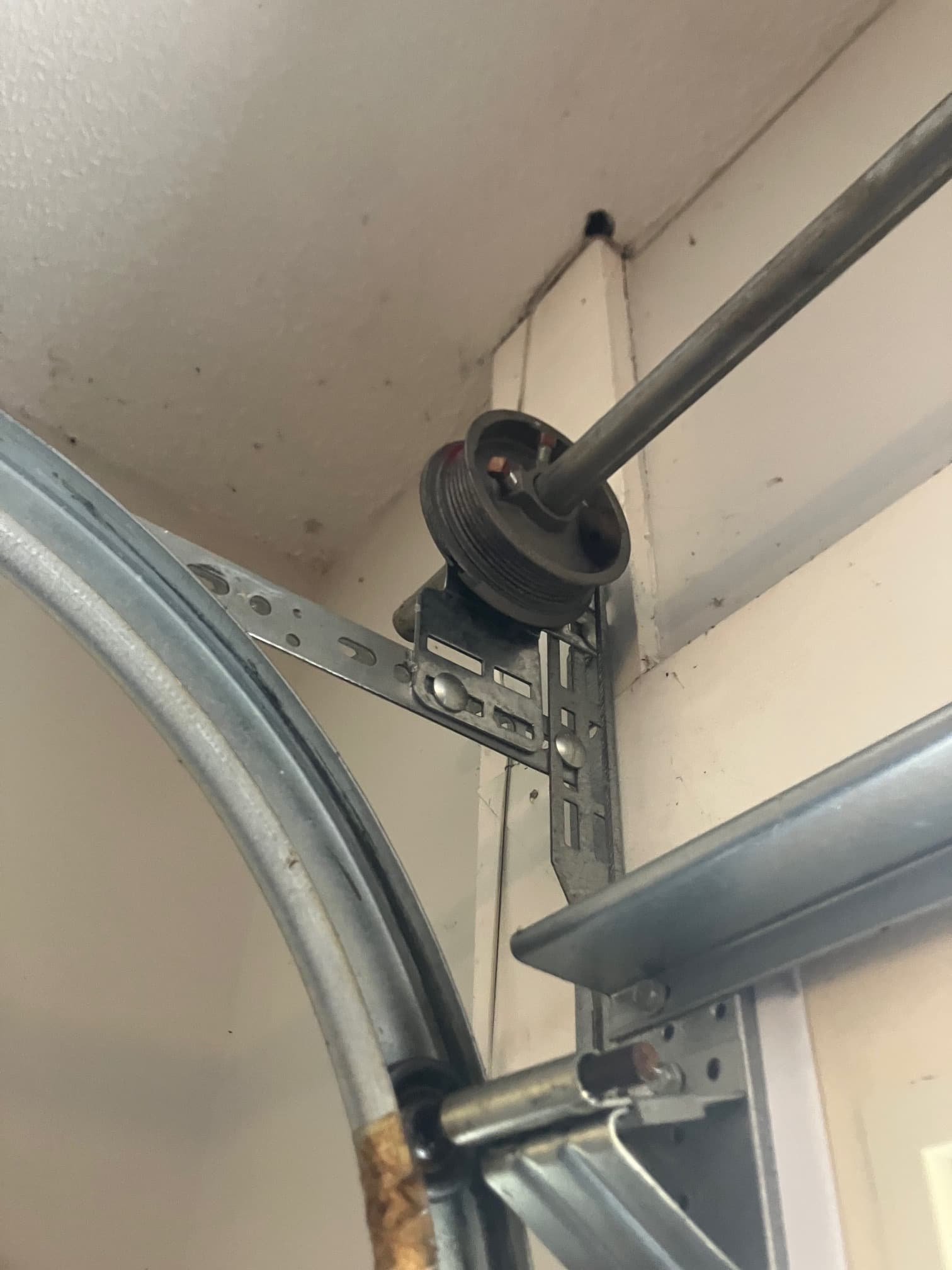 Dislodged garage door lift cable unspooled from cable drum