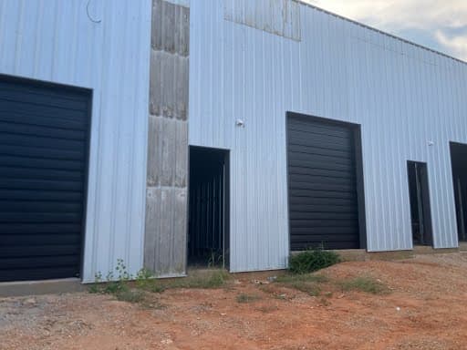 Two commercial roll-up garage doors installed on corrugated metal exterior