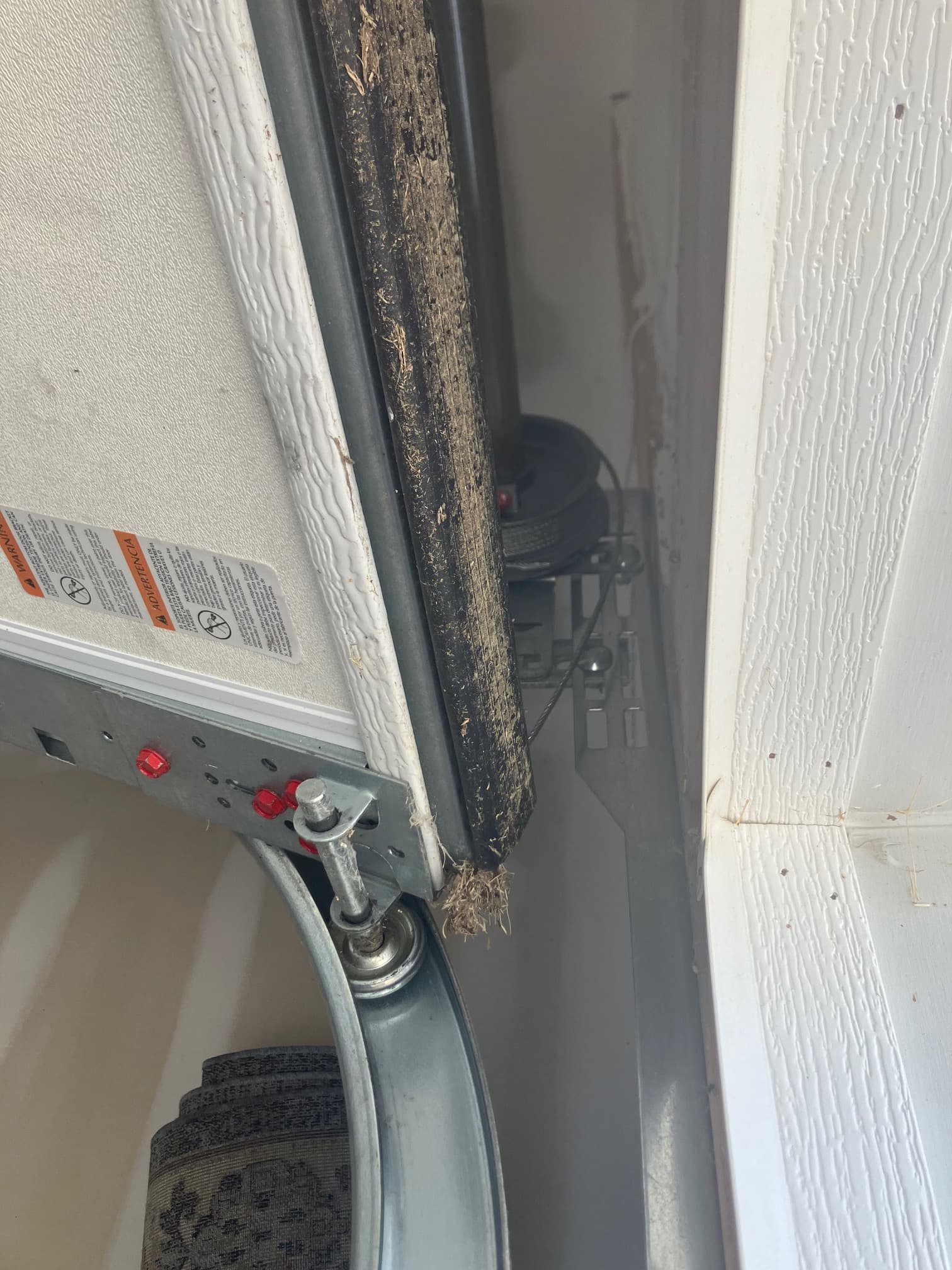 Frayed weather seal near roller track bracket
