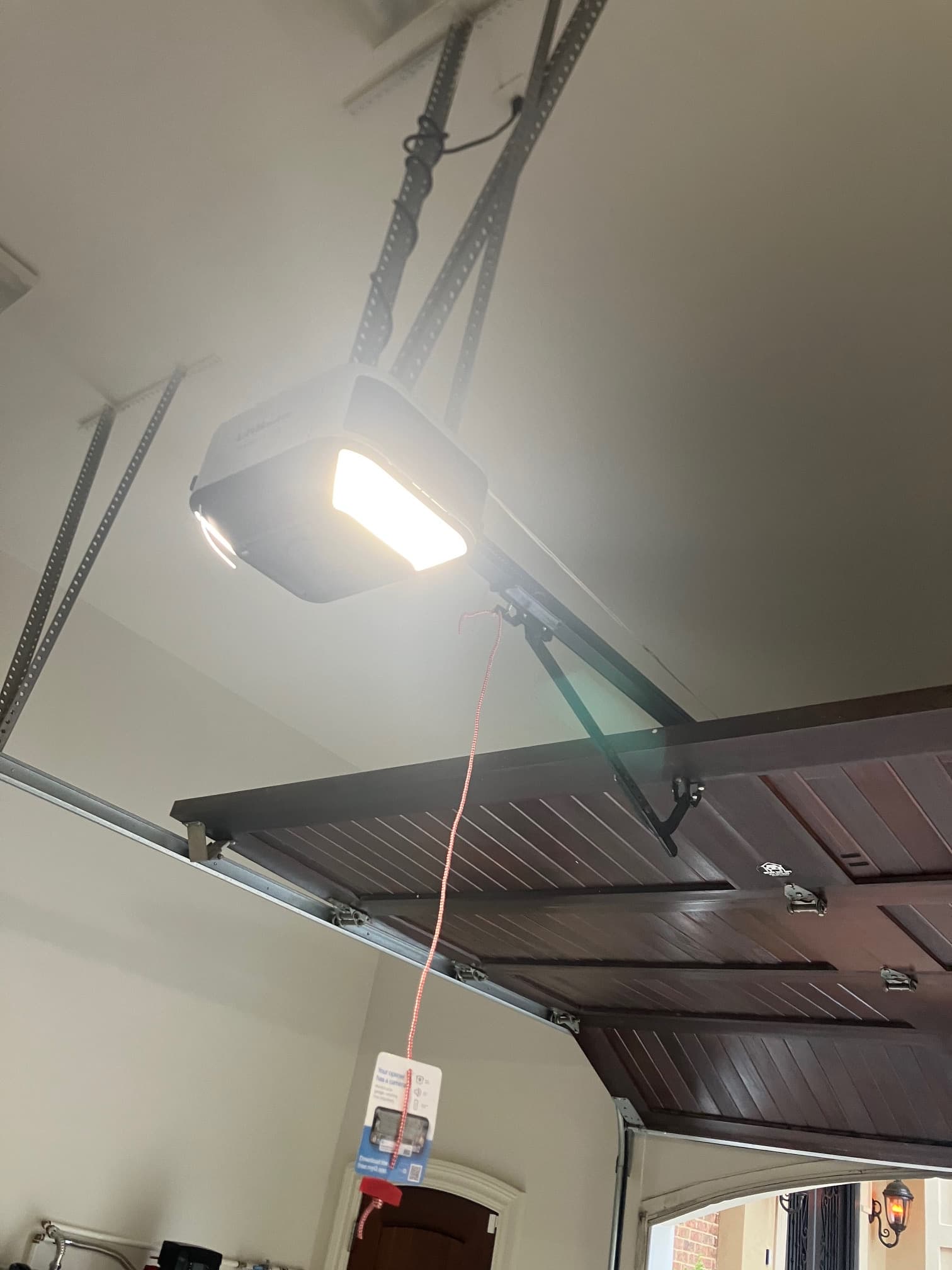 Installed garage door opener motor head with safety release cord and tag